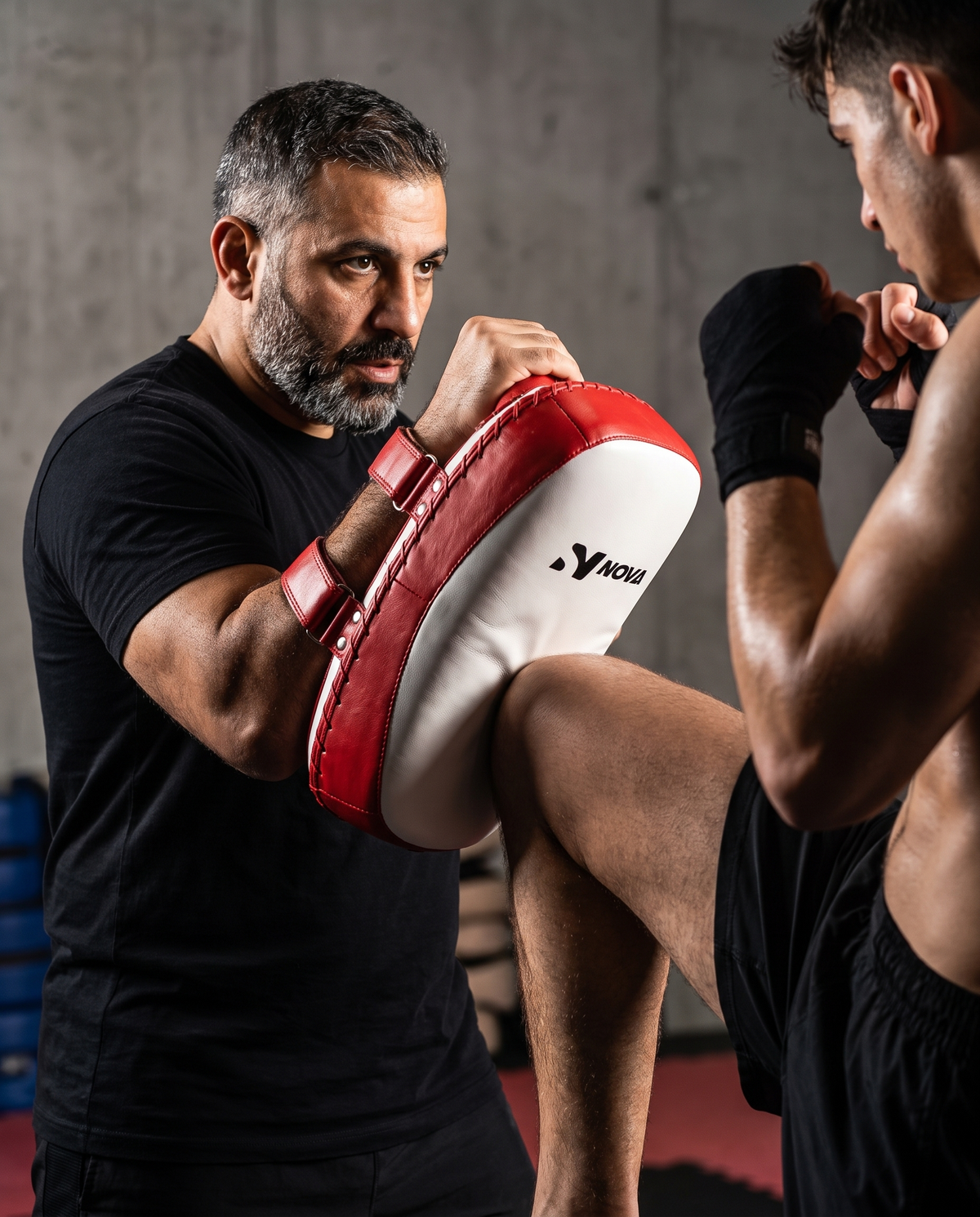 Coach catching a kick on a NOVA red and white leather curved arm pad during pad work — Arm Pads from Nova Sports Mauritius
