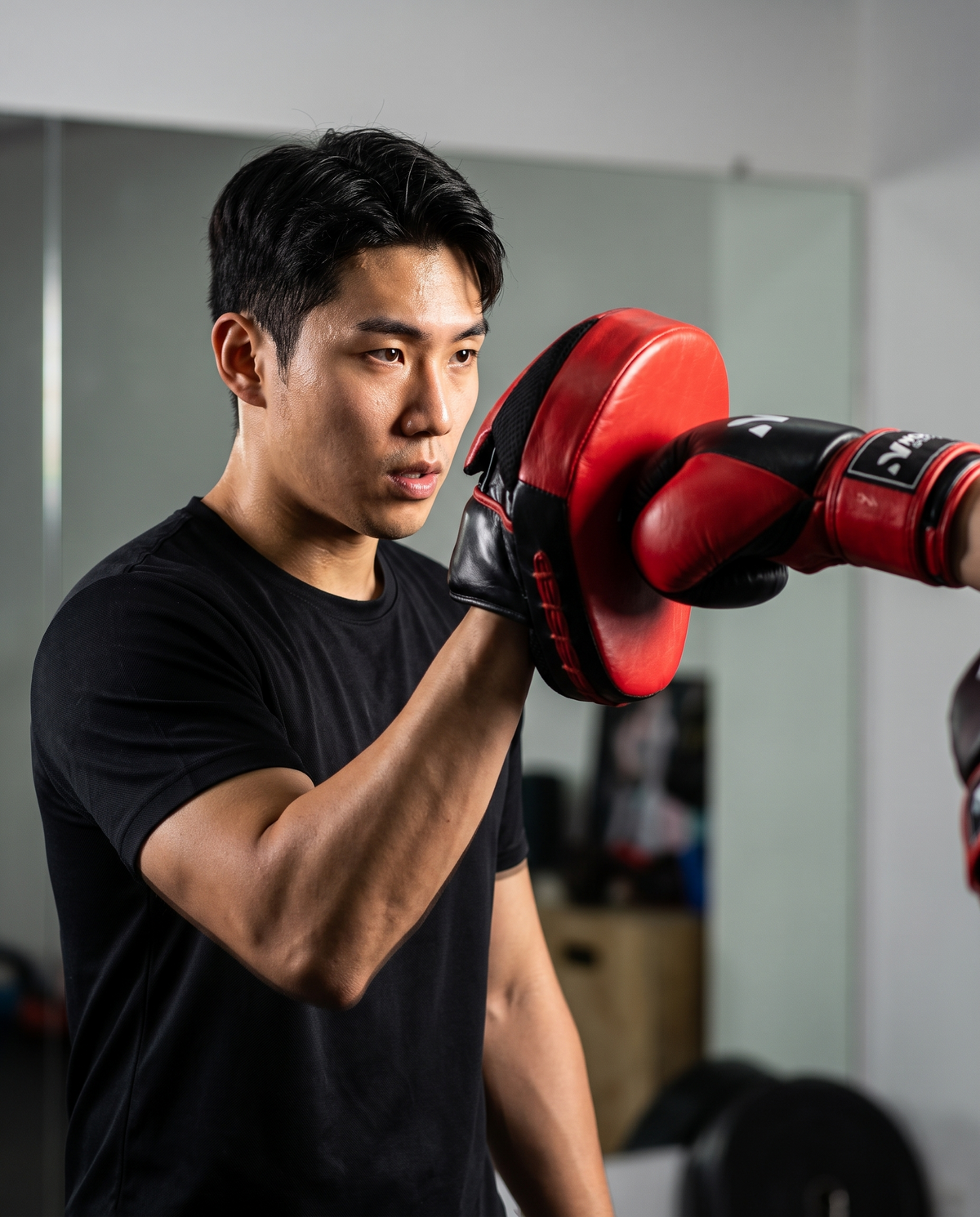Coach holding a NOVA red and black leather focus mitt as a partner throws a punch — Focus Pads & Mitts from Nova Sports Mauritius
