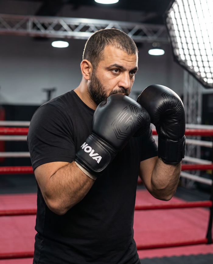 Coach in ready guard wearing NOVA all-black embossed boxing gloves — Gloves available in Mauritius

