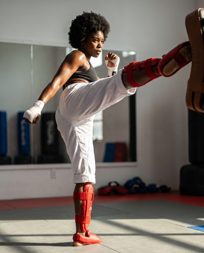 Athlete mid-roundhouse-kick wearing NOVA red karate shin and foot guards — Shin & Foot Guards available in Mauritius
