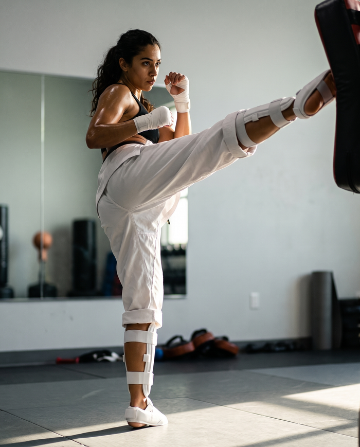 Athlete mid-roundhouse-kick wearing NOVA white karate shin and foot guards — Shin & Foot Guards available in Mauritius

