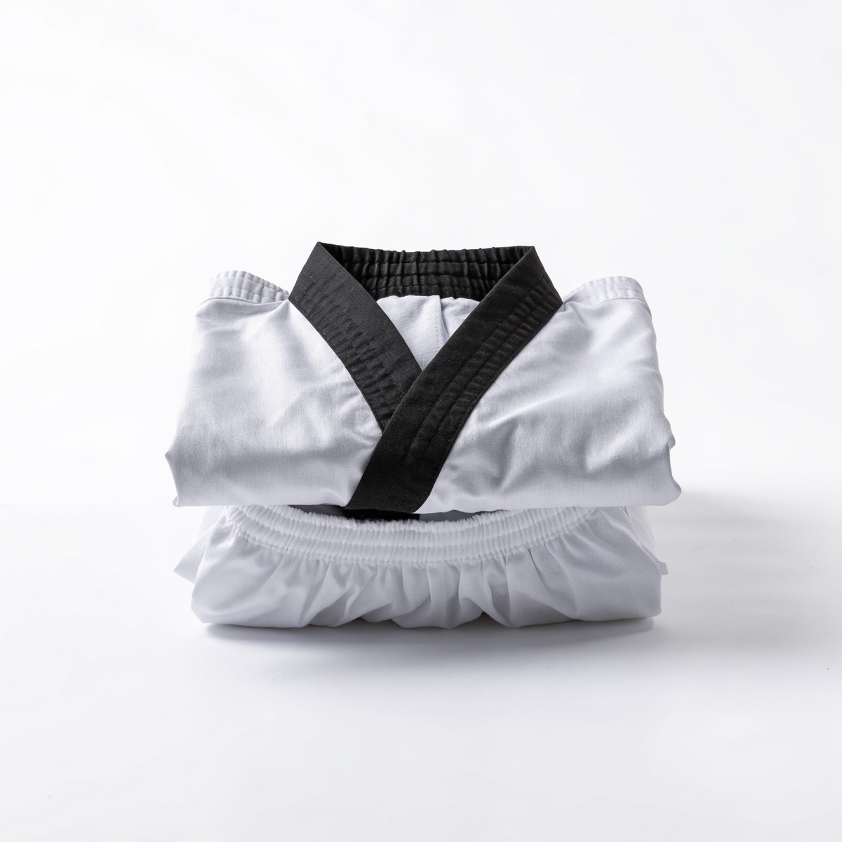 Nova Sports taekwondo dobok — white V-neck jacket with black collar and white trousers, folded on a white background — Uniforms from Nova Sports Mauritius
